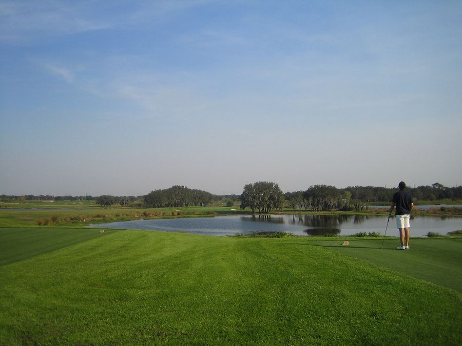 Golfer looking out over a lake from the tee