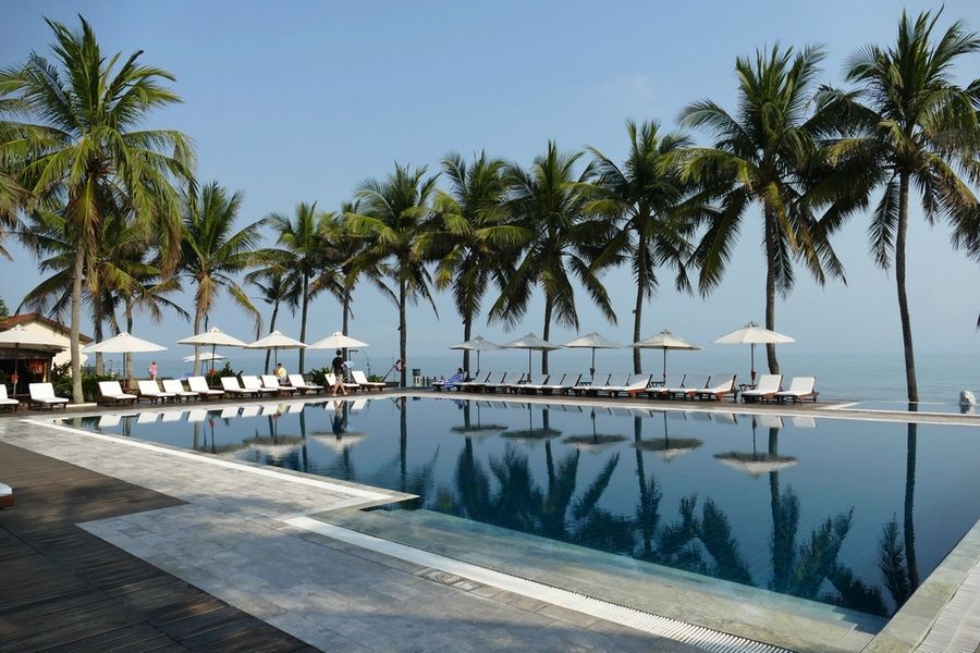 Resort pool lined with palms and umbrellas